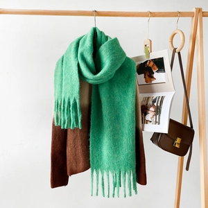 Close-up detail of green chunky knit mohair scarf with soft fringe and thick texture