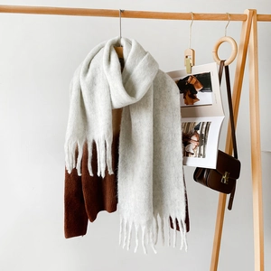 Close-up of thick light gray scarf featuring soft brushed texture and long tassels