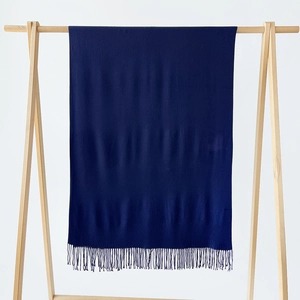 Detail of dark blue cashmere-like scarf with fringe hanging on a wooden display