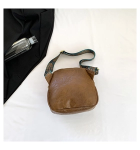 Detail der braunen Vintage-Leder-Schalentasche mit buntem ethnischem Stickgurt