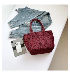 Flat lay of a red leopard print canvas tote bag with a denim jacket and modern gadgets