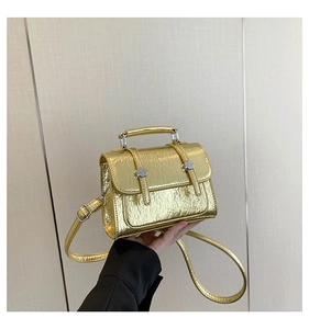 Detail shot of the gold crinkled leather texture and silver buckle on this messenger bag