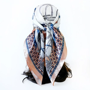 Detailed view of women silk-like scarf tied as a hair accessory with classic chain print