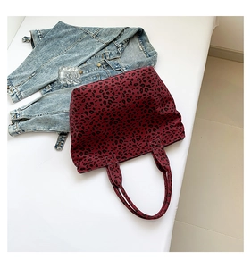 Flat lay view of a dark red leopard print canvas tote bag next to a denim jacket