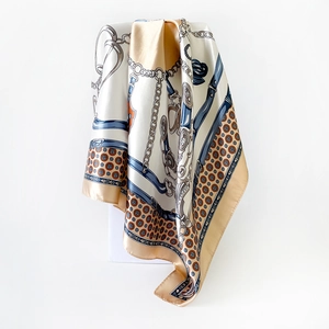 Detail of silk-satin scarf featuring classic horse chain print and golden equestrian patterns