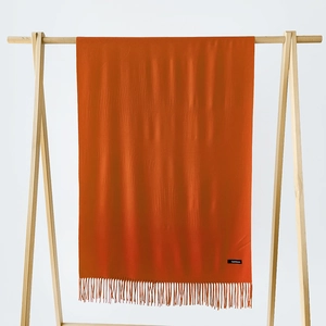 Detail of orange cashmere scarf showing soft knit texture and fringe tassels