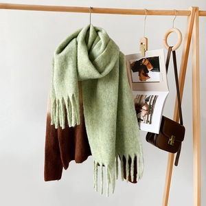 Detail of light green thick knit scarf with long tassels and stylish mohair texture