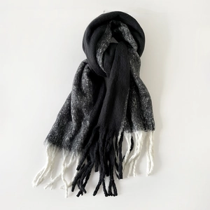 Detail of knit mohair scarf featuring black grey patchwork design and white tassels