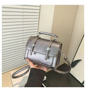 Detail of silver metallic textured crossbody bag with pleated finish and metal hardware