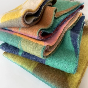 Close-up van dikke mohair sjaal met kleurrijke geometrische patronen en zachte franjes