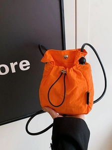 Vibrant orange nylon drawstring bucket bag with silver snap button and sleek black strap