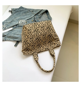 Close-up of leopard print canvas tote bag on white surface with denim jacket detail