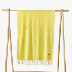 Detail of soft yellow cashmere scarf with elegant fringe trim and fabric composition label