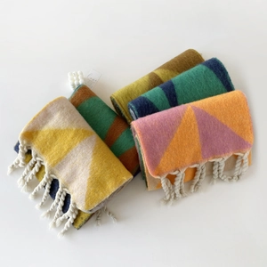 Detailoverzicht van geometrische mohair sjaals met dikke witte kwastjes en kleurmix