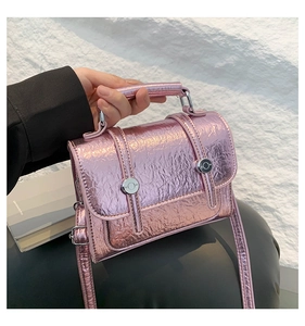 Detail of metallic pink messenger bag with cracked texture and silver buckle accents