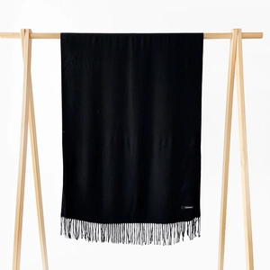 Close-up of black cashmere scarf with elegant fringe detail and material label