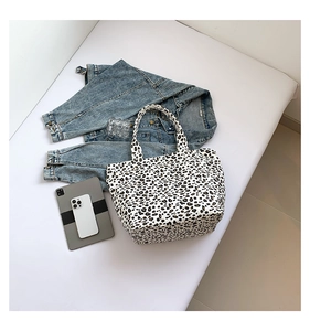 Detail view of leopard print canvas tote bag with urban lifestyle accessories and denim jacket