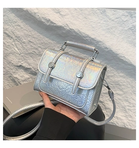 Detail of silver laser textured messenger bag with pleated surface and metal buckle