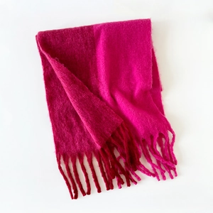 Close-up of soft mohair knit scarf with fringe details in vibrant rose pink