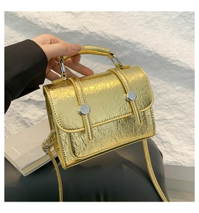 Close-up of golden metallic cracked texture leather messenger bag with round buckle