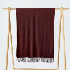 Detail of soft dark red cashmere scarf with neat fringe and authentic material label