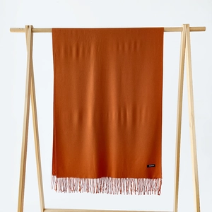 Detail view of caramel cashmere scarf texture with fine tassels and fabric label