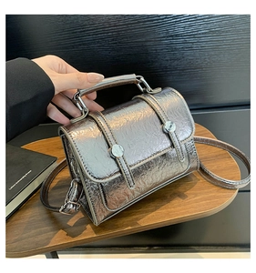 Detail of silver metallic wrinkled texture and round buckle on a retro satchel bag