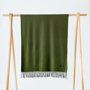 Detail of dark green cashmere scarf with fringe tassels and authentic material label