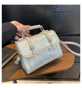 Close-up of holographic silver messenger bag showing wrinkled texture and metal buckles