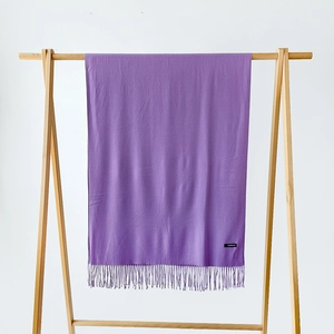Detailed close-up of a purple cashmere scarf with tassels on a wooden hanger