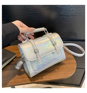 Detail of laser iridescent silver messenger bag with textured surface and top handle