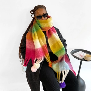 Detail showing the colorful rainbow plaid pattern and soft pompoms on a winter scarf