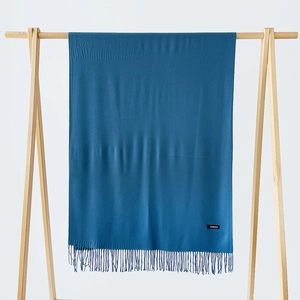 Detailed texture of dark blue cashmere scarf with elegant fringe and woven label