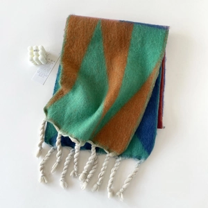 Detail van een kleurrijke geometrische mohair sjaal met dikke witte kwastjes op wit