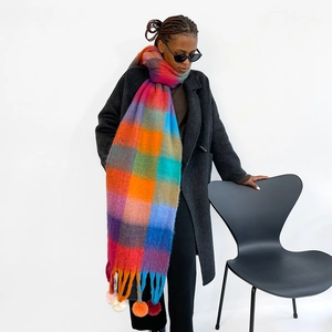 Detail of colorful plaid scarf with handmade pom-poms and fringe tassels on ends
