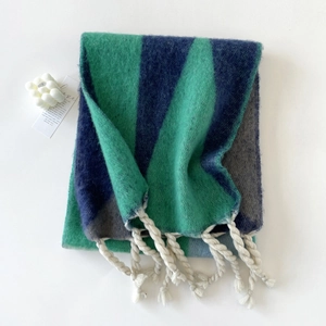 Detail van blauw-groene mohair sjaal met dikke witte franjes en zachte textuur