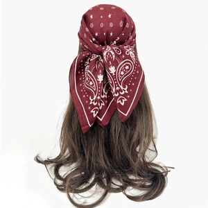 Detail of burgundy cashew flower scarf with star patterns on long brown wavy hair