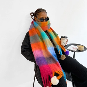 Detail of colorful rainbow plaid scarf with long tassels and soft handmade pom-poms