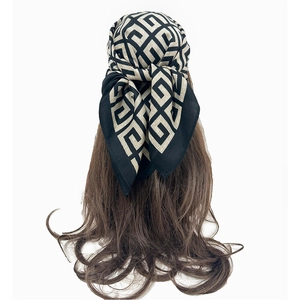 Elegant black and beige geometric silk scarf worn as a stylish headband on brown hair