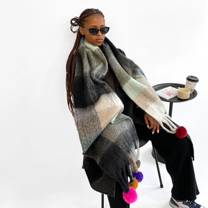 Close-up of thick plaid scarf featuring colorful oversized tassels and knit texture