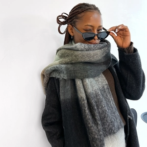 Detail of gray gradient thick winter scarf featuring soft knit texture and fringe edge
