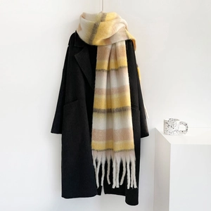 Detalle de bufanda de mohair a rayas con flecos y un abrigo de lana negro clásico