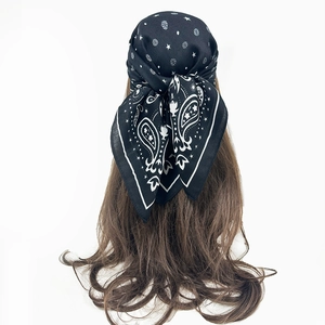 Classic black and white paisley silk scarf tied as a headband on wavy brown hair