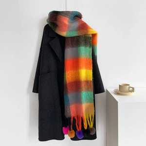 Detail of rainbow plaid scarf with colorful pompom tassels on a black wool coat