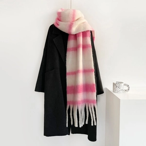 Detalle de textura de bufanda de mohair rosa y beige con flecos sobre un abrigo negro