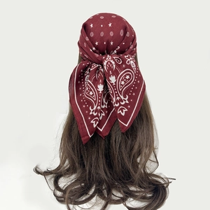 Close-up of the vintage paisley pattern on a deep red cotton-blend square headscarf