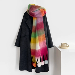 Detail of colorful plaid winter scarf with vibrant multi-color pom-pom tassels