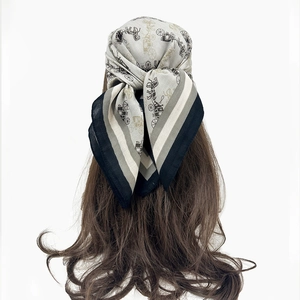 Detail of grey paisley headscarf with carriage print tied as a stylish hair accessory