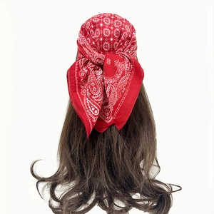 Close-up of red paisley pattern bandana tied on brown wavy hair in retro street style