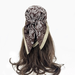 Detail of dark brown paisley bandana tied on long hair with khaki border accent